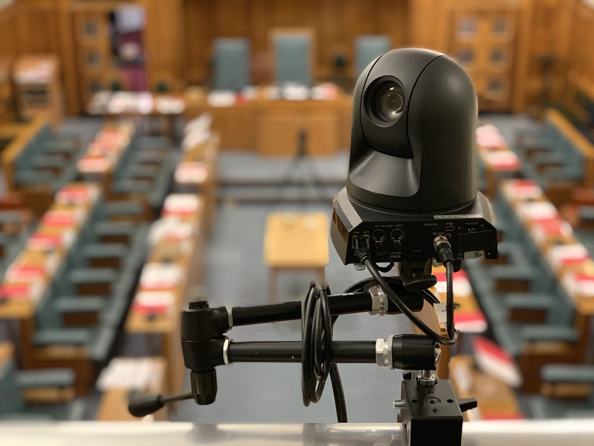 Reference image: PTZ camera and connected SDI and network cables overlooking a council chamber